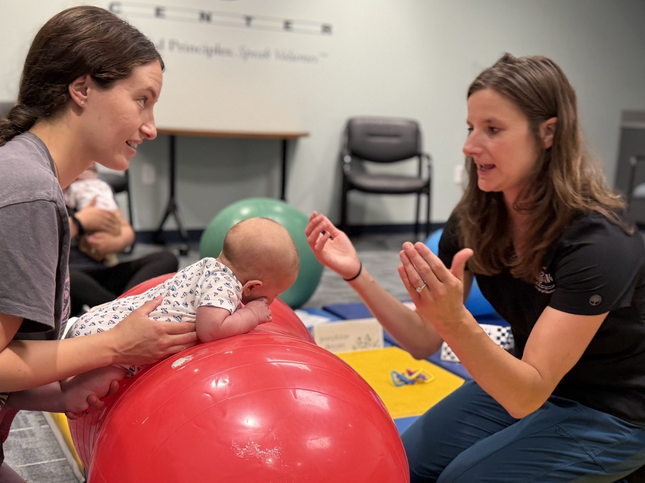 Jennifer Jones PT, DPT, PCS | Board Certified Pediatric Clinical Specialist and Pediatric Physical Therapist with mom and baby at our springtime Tummy Time Champions workshop.