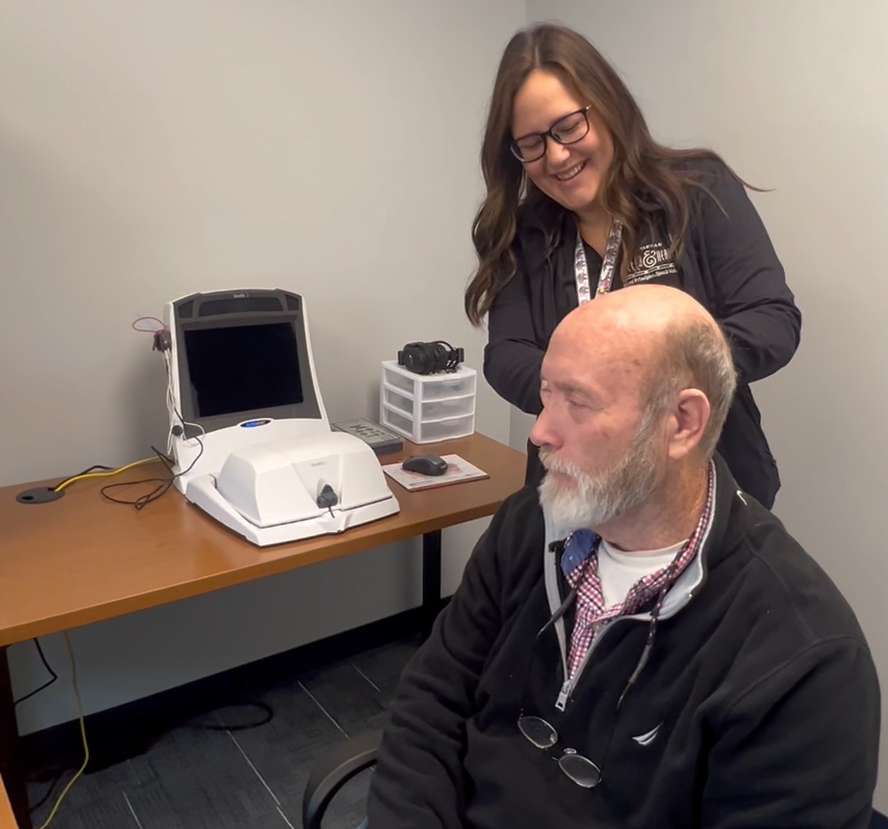 Maddie Schmidt, Au.D. | Audiologist offering hearing aid maintenance and fitting to a male senior citizen at Savannah Speech & Hearing Center.