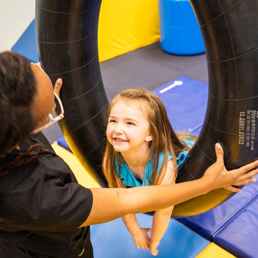 Rehabilitation therapy client smiling up at her clinician, Diamond Rashad, OTR in the occupational therapy gym at Savannah Speech & Hearing center